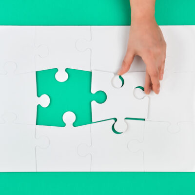 hand holds the missing element in the game of puzzles on a green background